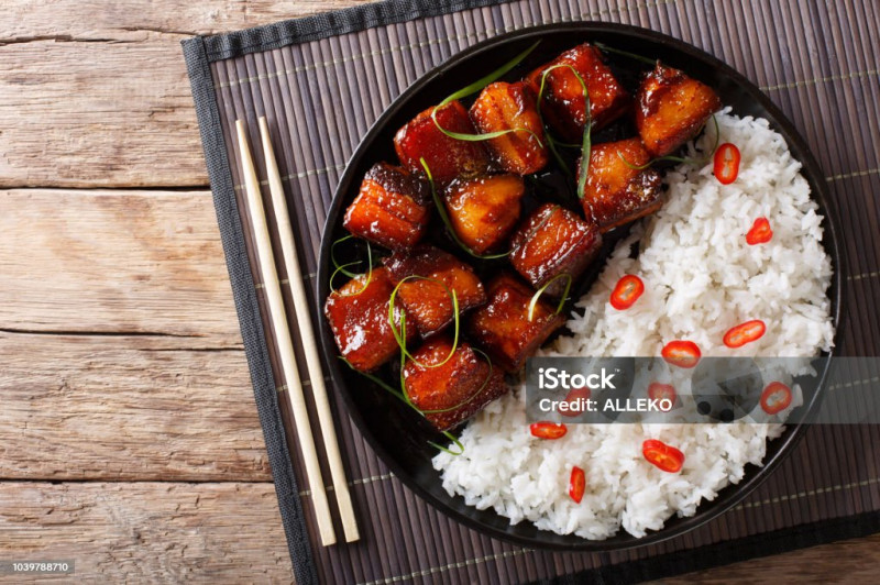 Vietnamese spicy caramel pork belly with rice closeup on a plate on a table. Horizontal top view from above